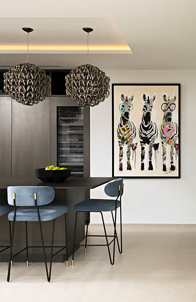 Cucina moderna con sgabelli da bar blu, decorazioni zebrate e lampadari decorativi.