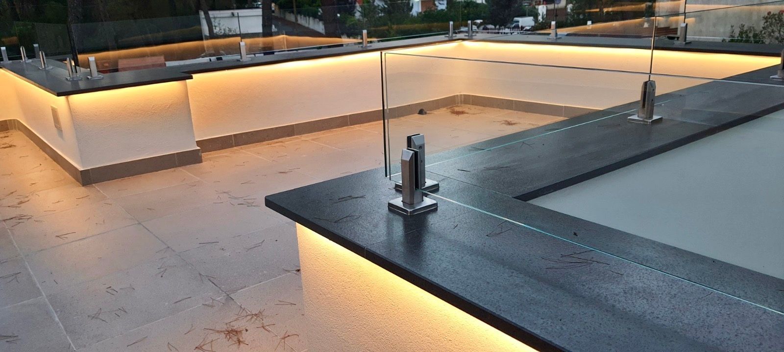 Tetto con perimetro illuminato, caratterizzato da un bordo in pietra scura e infissi in metallo.