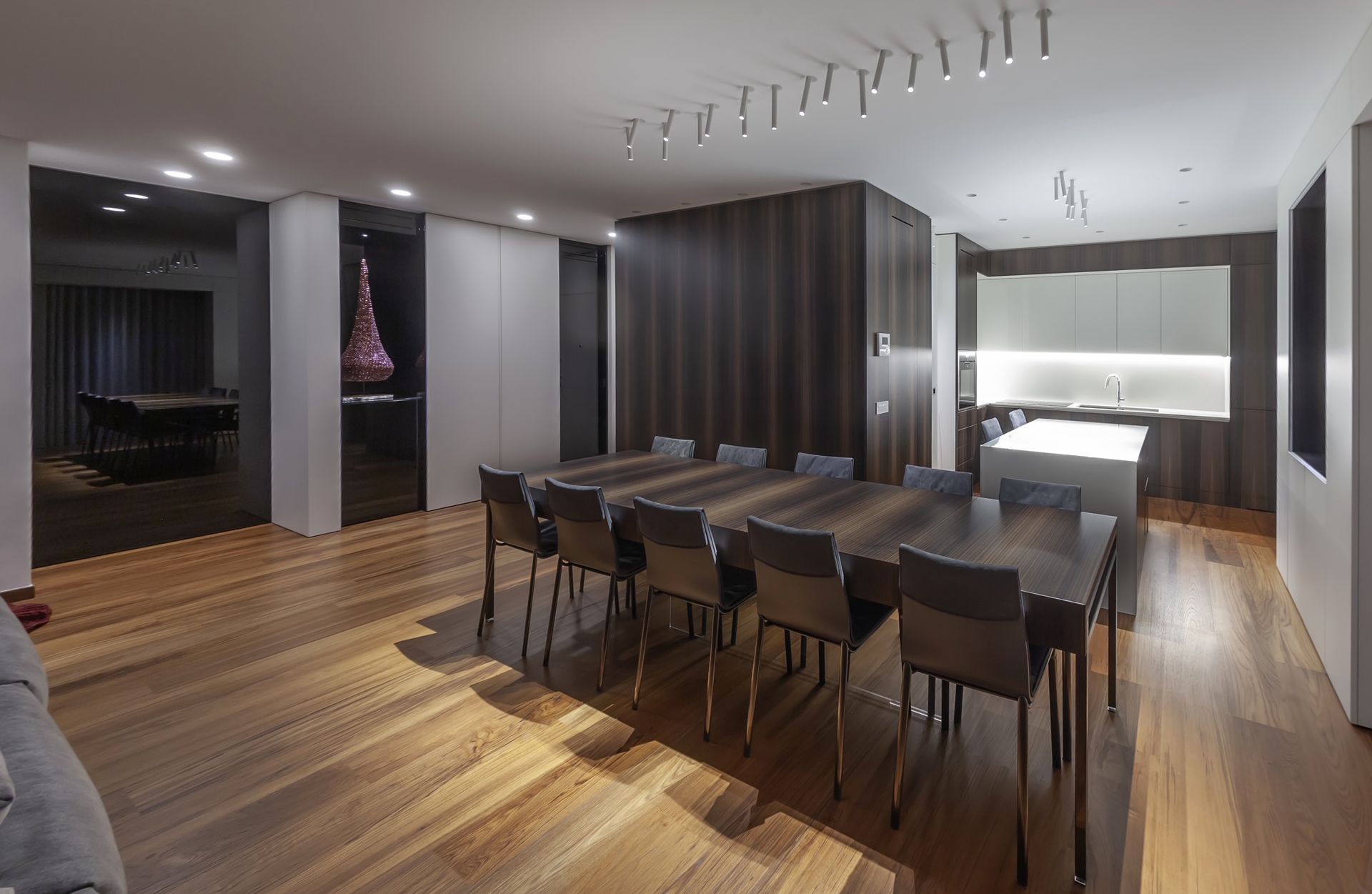 Moderna sala da pranzo con un lungo tavolo apparecchiato per numerosi ospiti, collegata alla cucina.