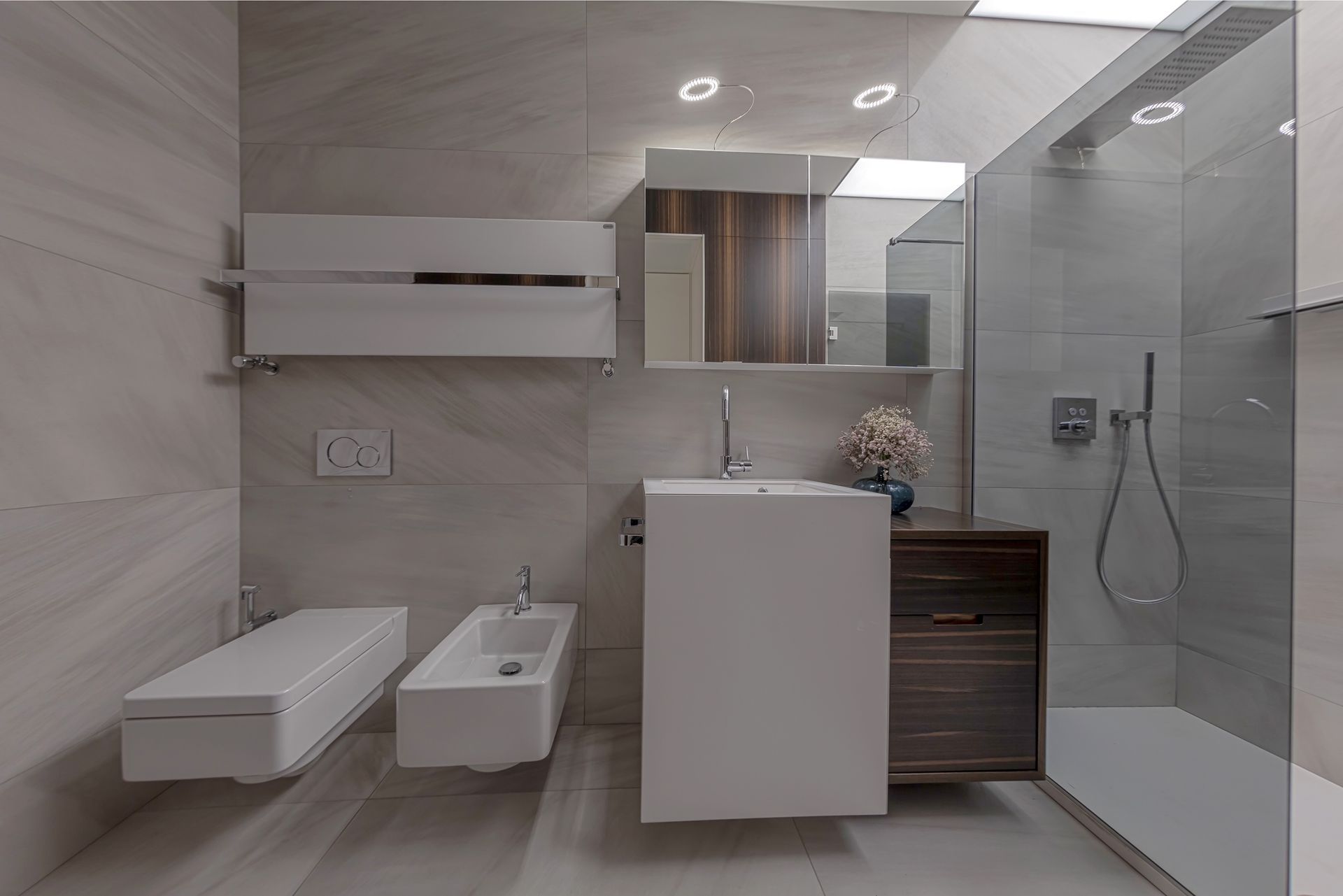 Bagno moderno con sanitari bianchi, doccia e mobiletto in legno scuro.