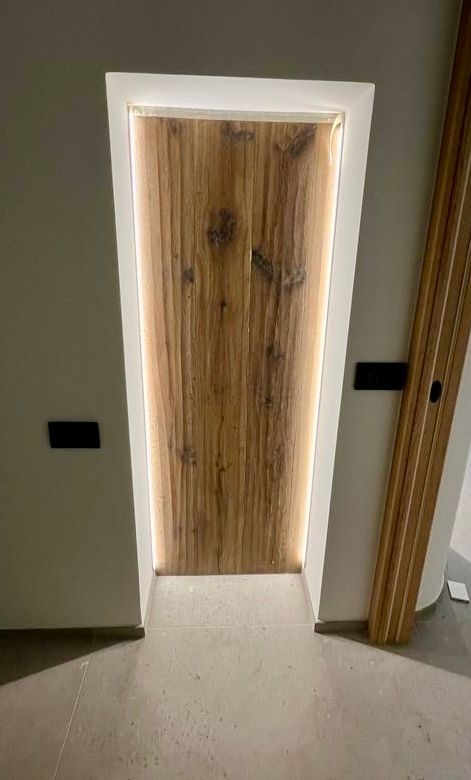 Porta in legno con venature verticali, incorniciata da una cornice bianca e retroilluminazione calda.