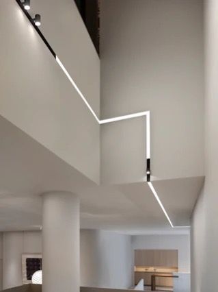 Vista interna con illuminazione a binario angolare su pareti bianche, che conduce a un controsoffitto incassato.