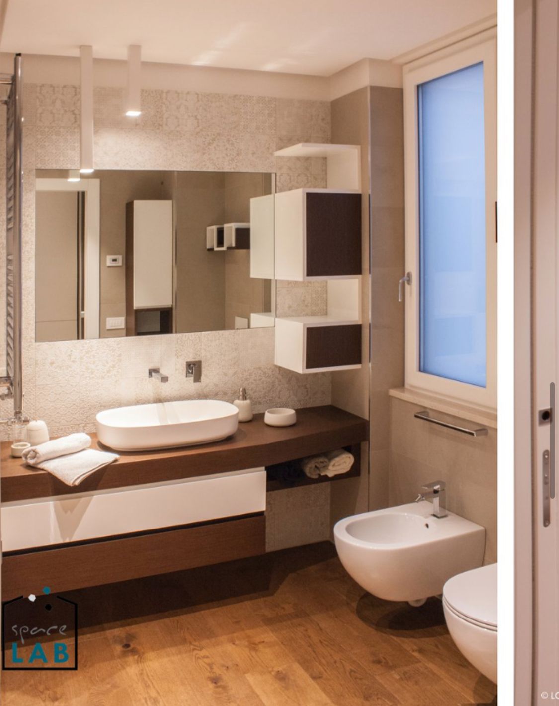Bagno moderno con mobiletto in legno, lavandino bianco e spazio per riporre gli oggetti. Dispone di bidet e WC.