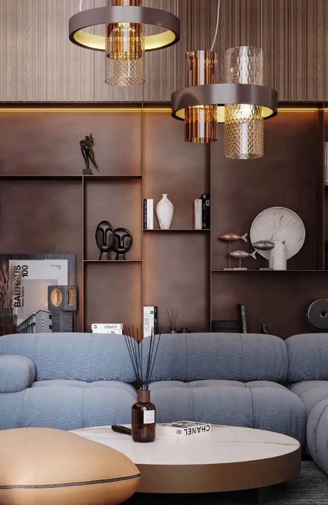 Soggiorno con divano blu, tavolino in marmo, scaffalature integrate e lampade a sospensione.