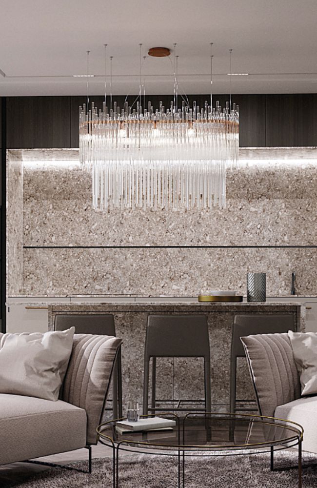 Soggiorno con lampadario di cristallo, divani dai colori chiari e un bar effetto marmo.