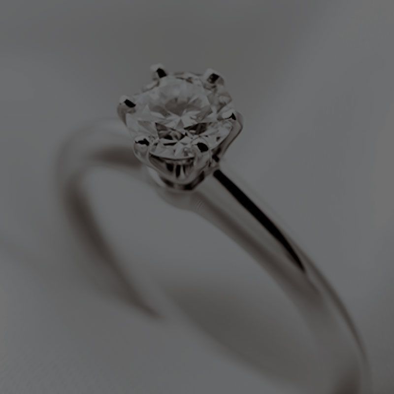 A close up of a diamond ring on a white surface.