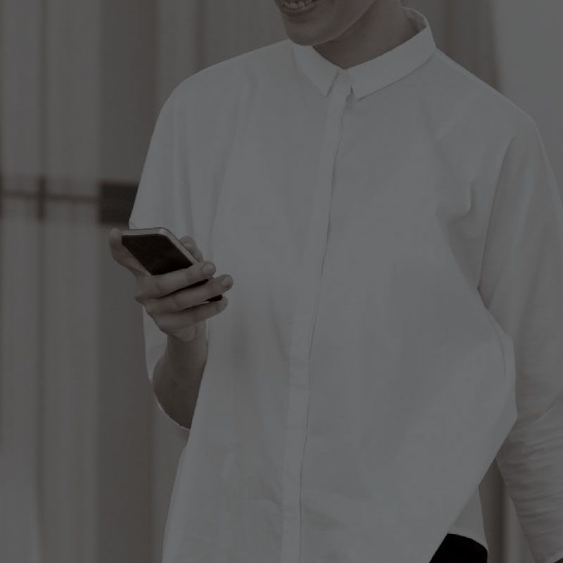 A man in a white shirt is holding a cell phone in his hand.