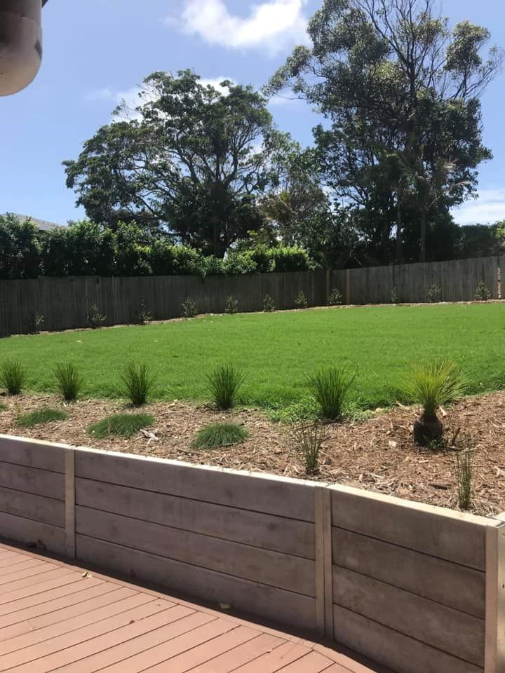 A Backyard Featuring a Wooden Retaining Wall, a Landscaped Garden Bed — Ballina Turf Farm in Tweed Heads, NSW