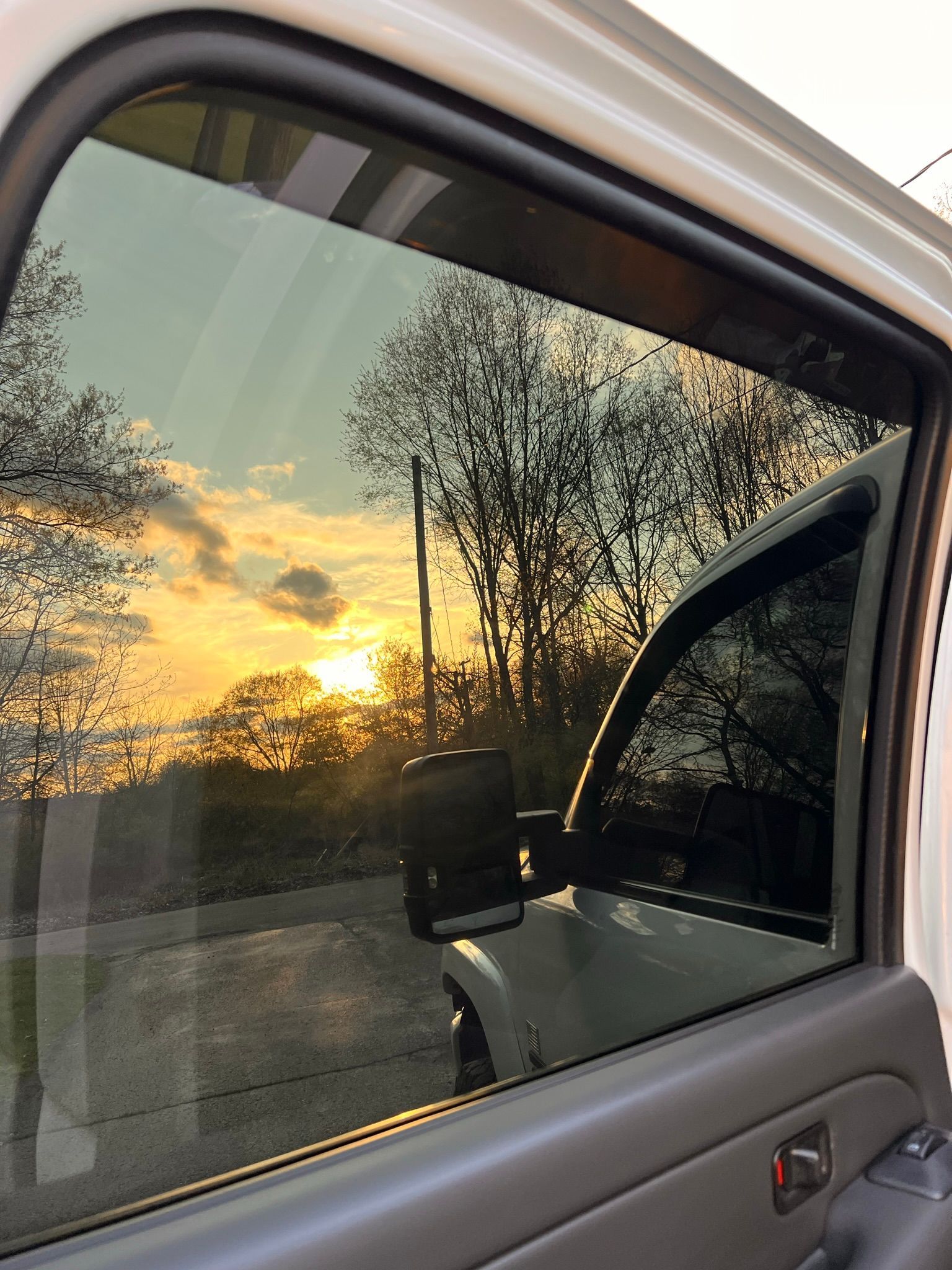 A sunset is reflected in the window of a truck.