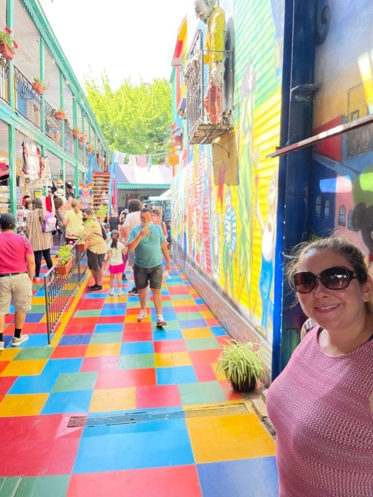 Colorful tiled alley with people walking, and a smiling woman in sunglasses in the foreground