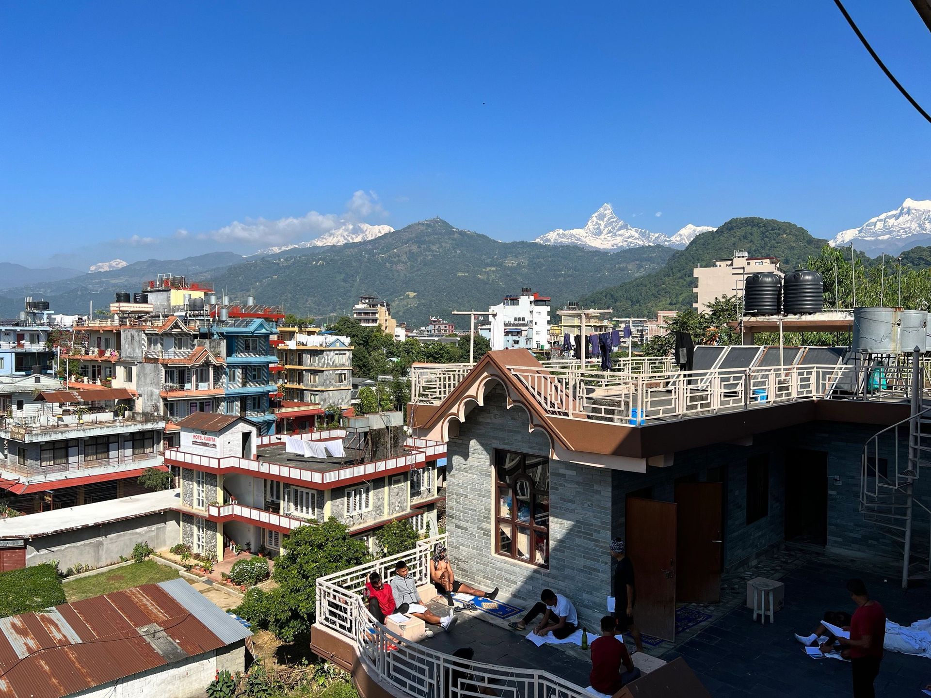 Mountain town rooftops under a clear blue sky, with snow-capped peaks in the distance.