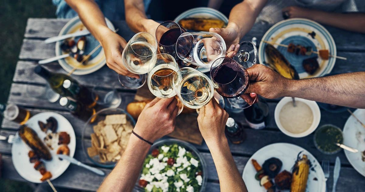 Friends clinking wine glasses over a table of assorted dishes at a festive meal