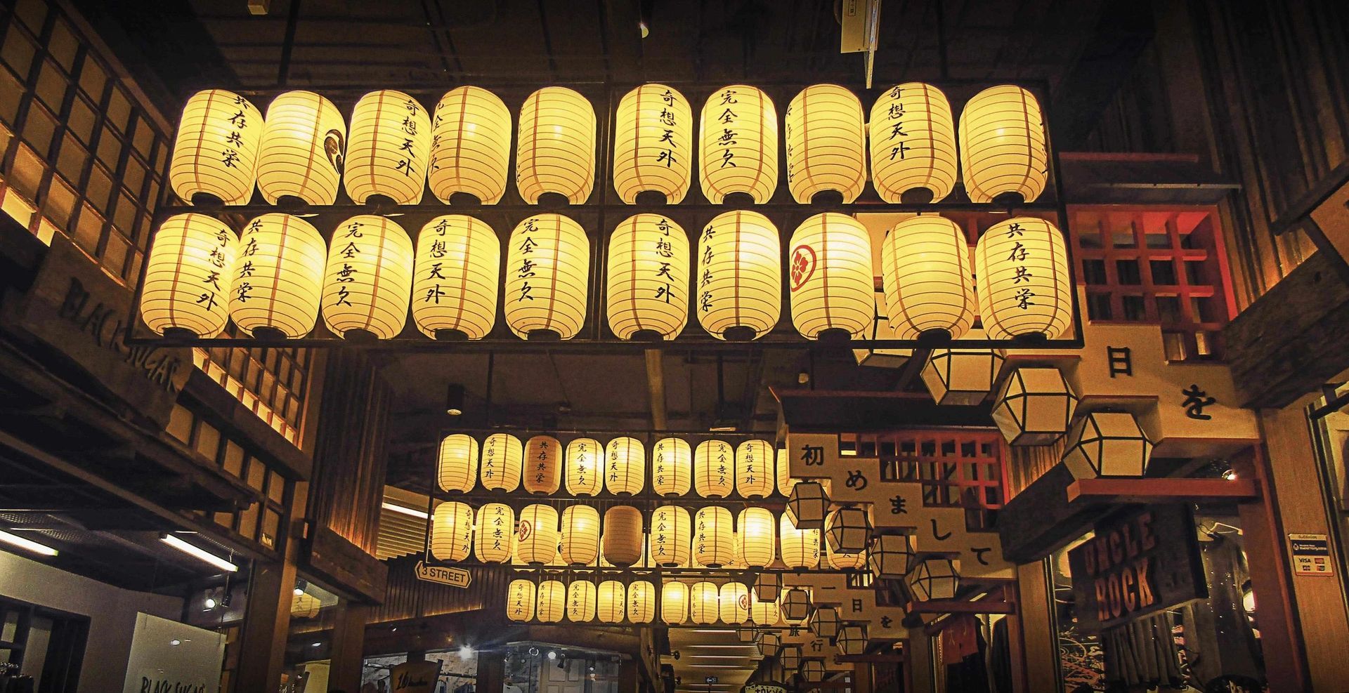 Rows of glowing paper lanterns hanging outside a traditional Japanese-style restaurant at night