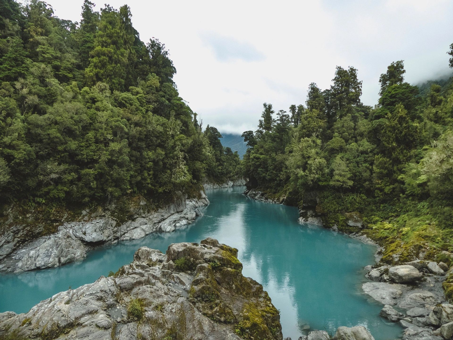 Turquoise river winding through a lush forested gorge with rocky banks