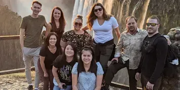 A group of people posing in front of a fountain outdoors, smiling at the camera.