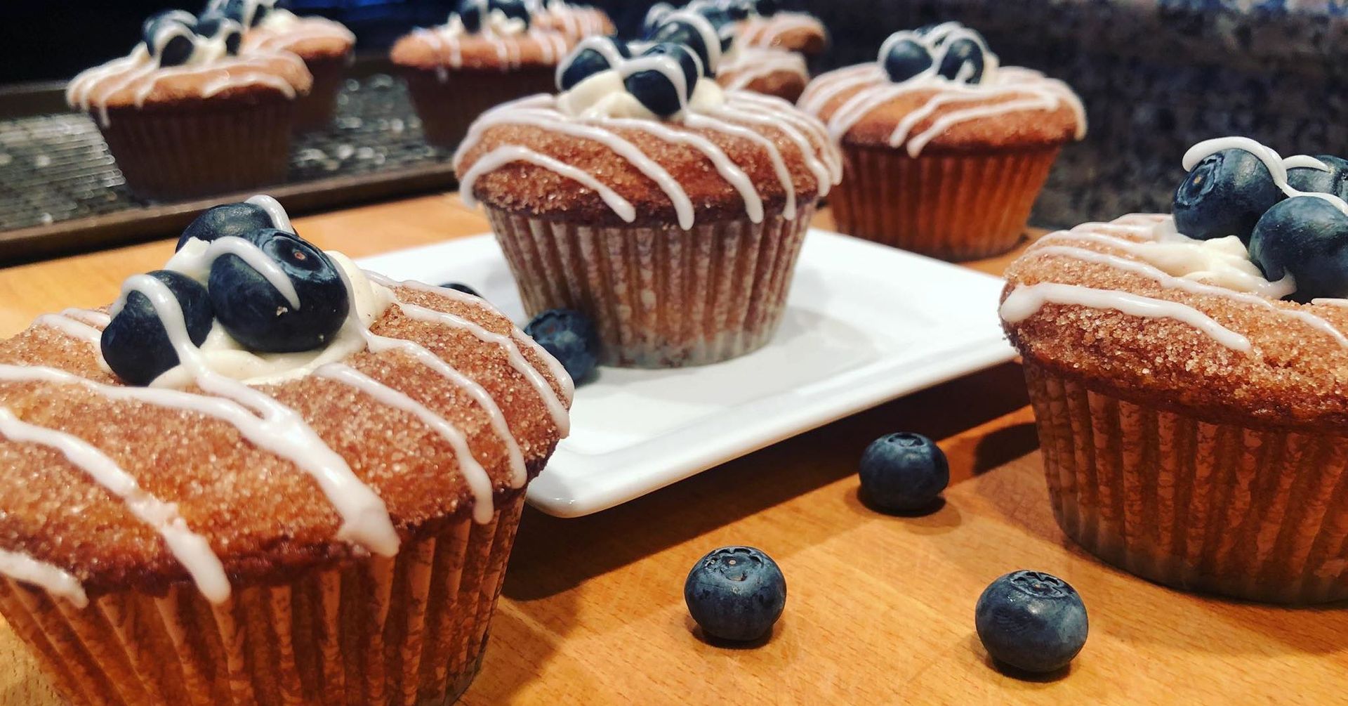 Blueberry muffins with white frosting and fresh blueberries.