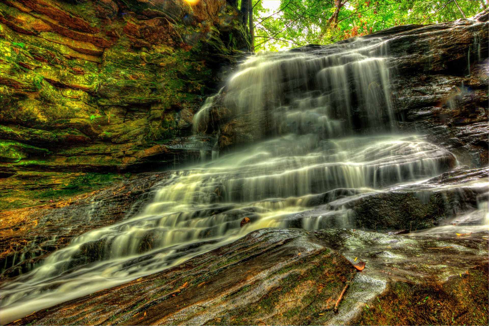 Small waterfall cascading over mossy rocks in a forest scene