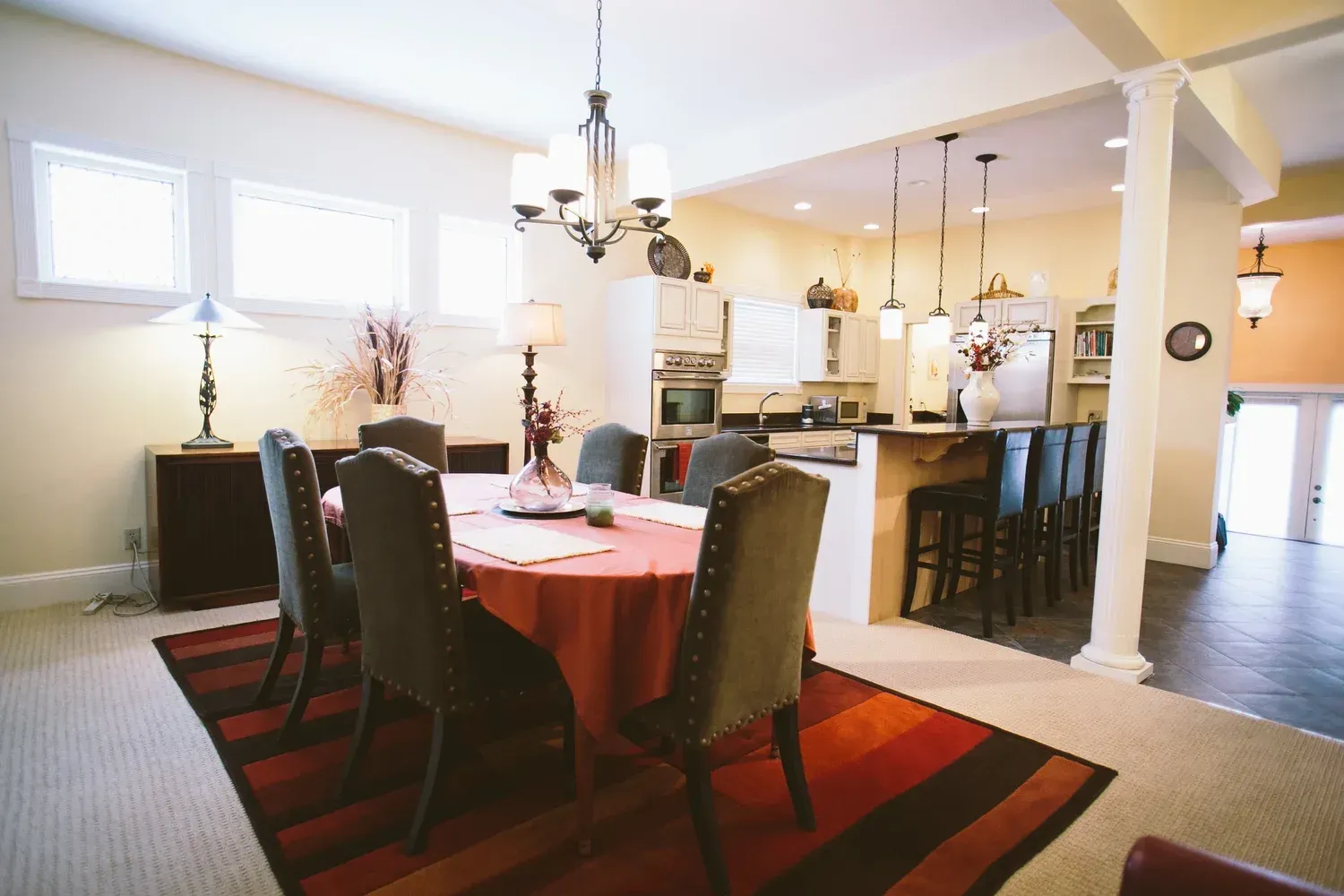 Dining room with a table, chairs, kitchen island, and light fixtures.