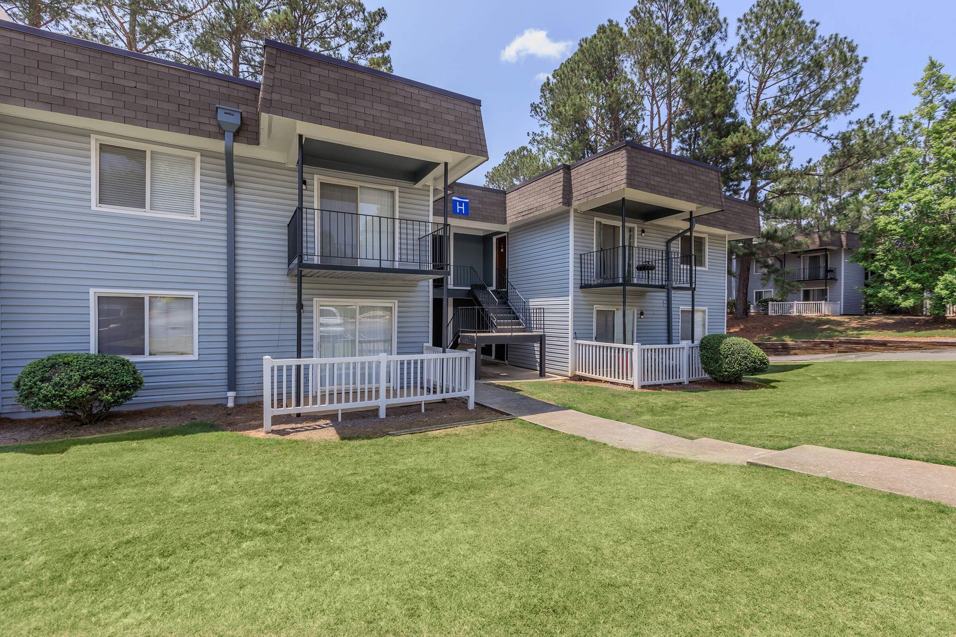 A row of apartment buildings with a lush green lawn in front of them.