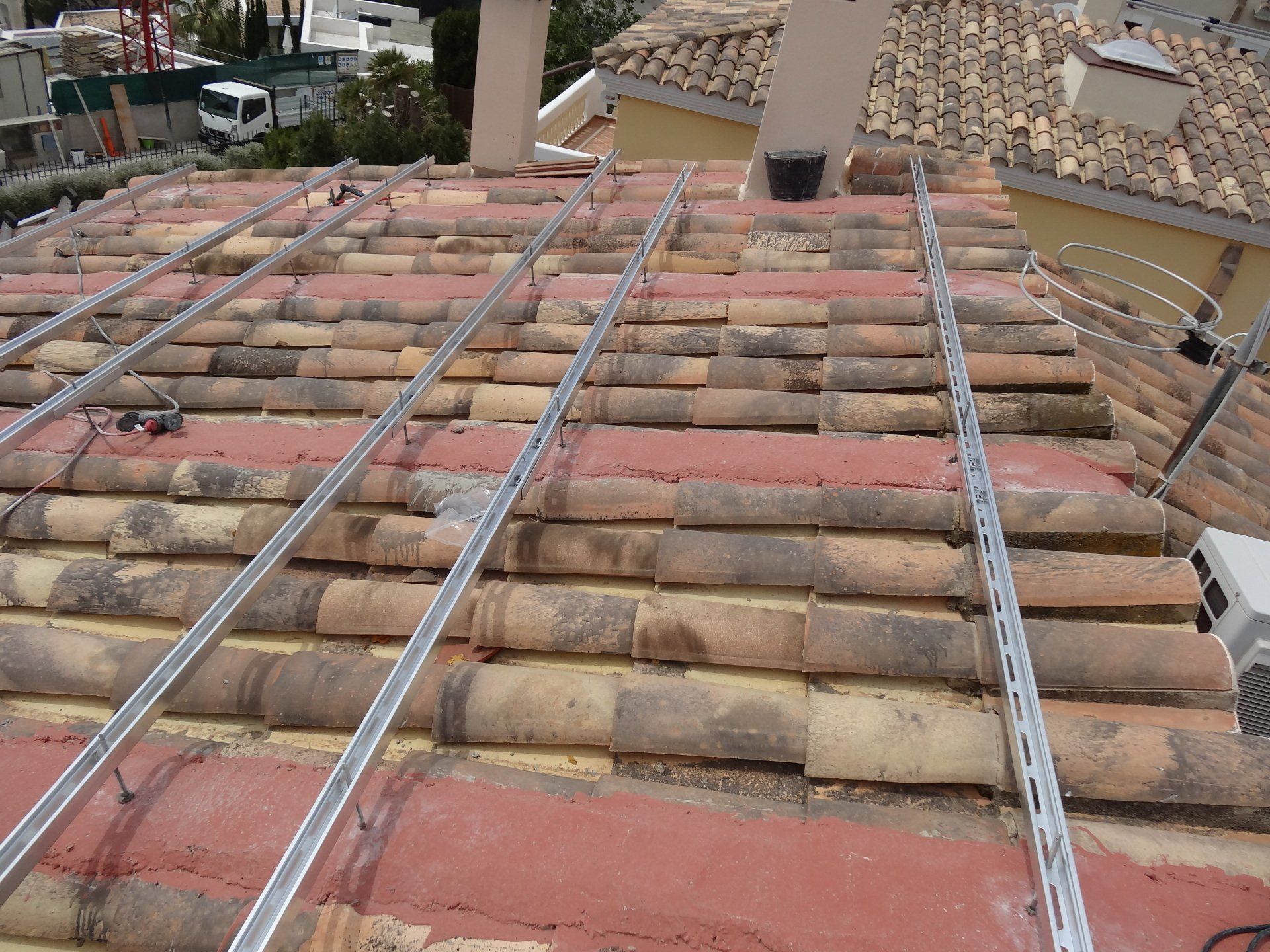 Rieles metálicos instalados sobre techo de tejas de arcilla, listos para instalación de paneles solares.