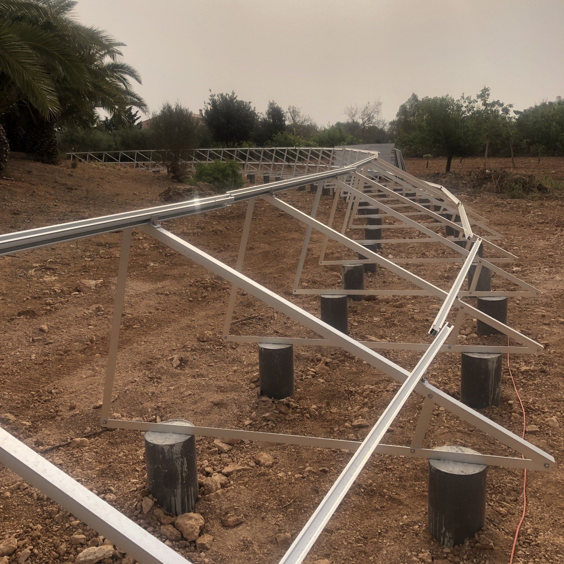 Sistema de montaje de paneles solares en construcción en terreno, con soportes de hormigón y marcos metálicos.