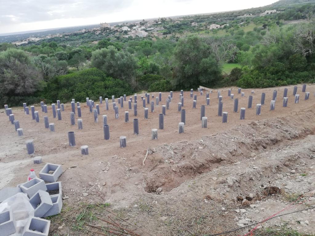 Sitio de construcción con numerosos pilares de hormigón en el suelo, a la espera de edificación.