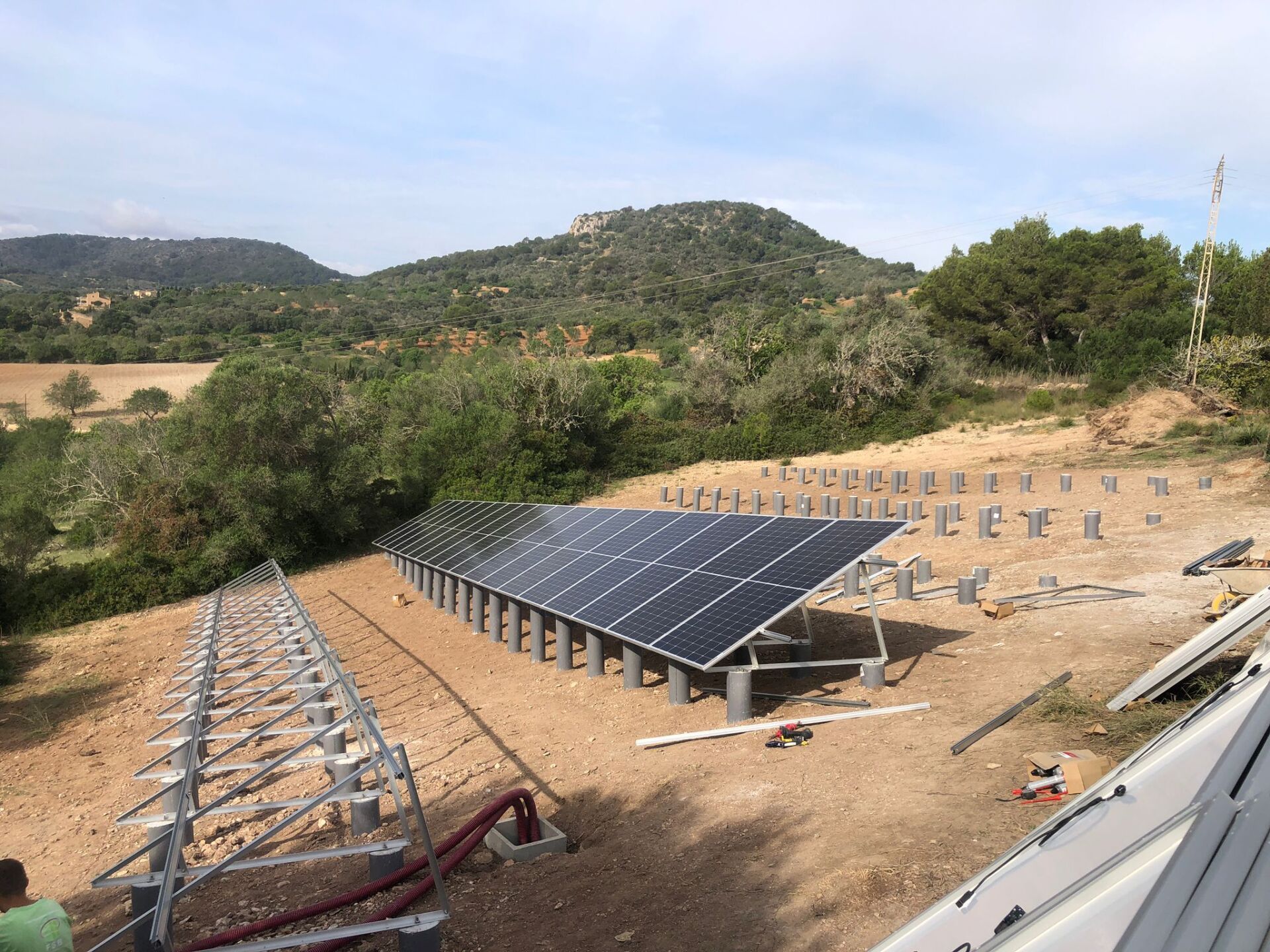 Instalación de paneles solares en progreso en una ladera con un fondo de montañas.