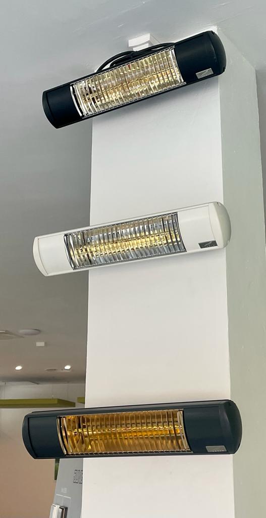 Three wall-mounted electric heaters, one white and two black, installed on a white column.