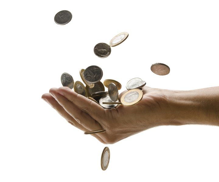 Mano atrapando monedas que caen.