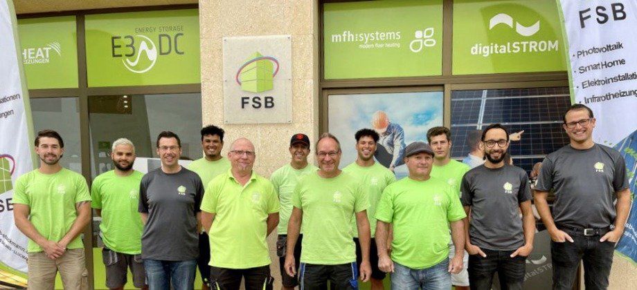 Un grupo de personas vestidas con camisetas verdes frente a un negocio con logotipos.