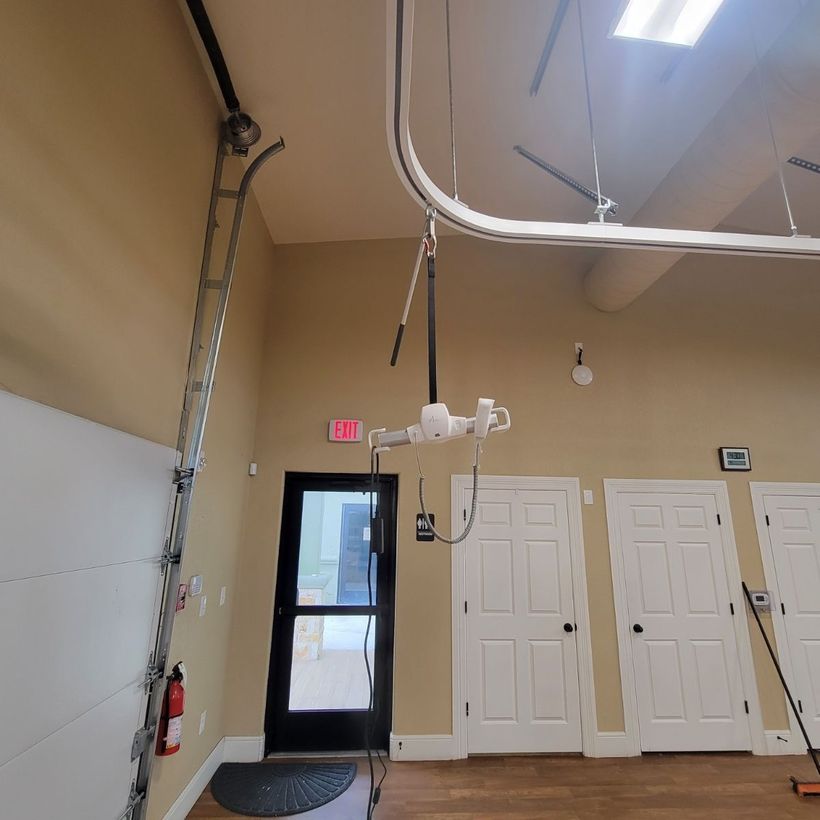 A room with a ladder and a lift hanging from the ceiling.