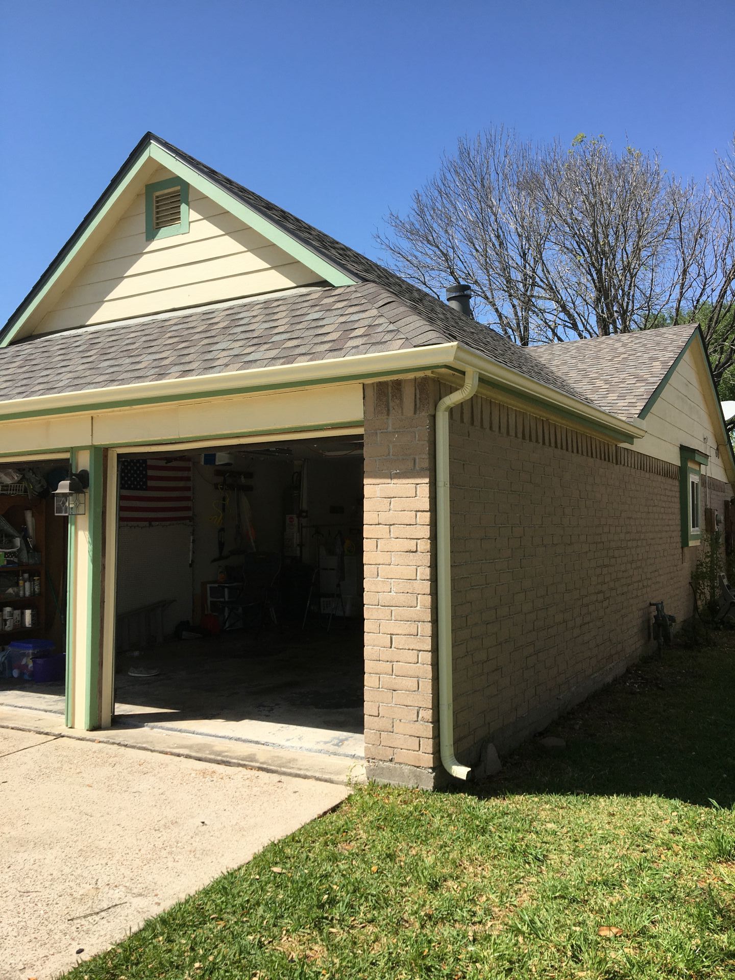 Garage attached to a house with an open bay and tan brick exterior.