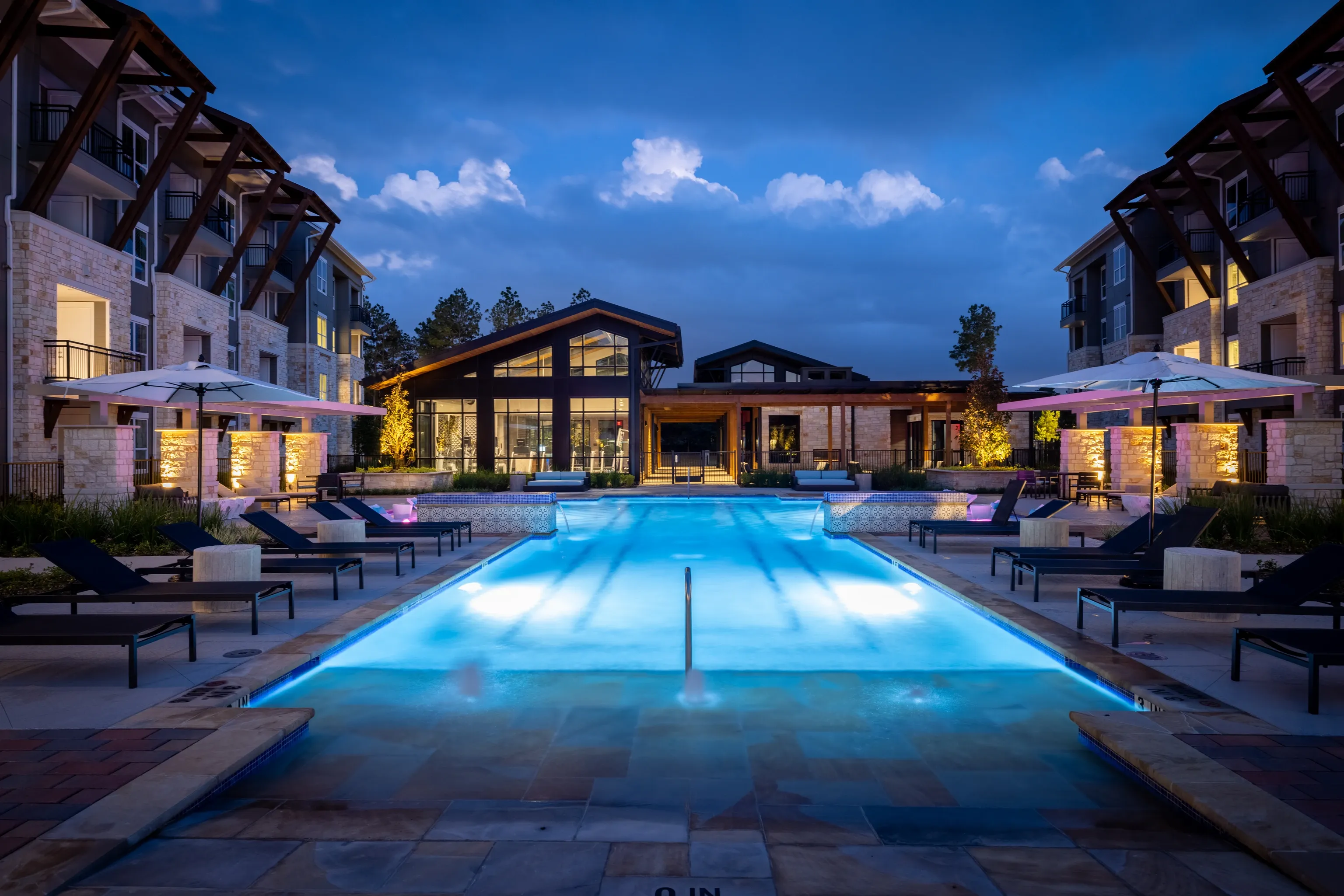 Outdoor swimming pool and lounge area at dusk.