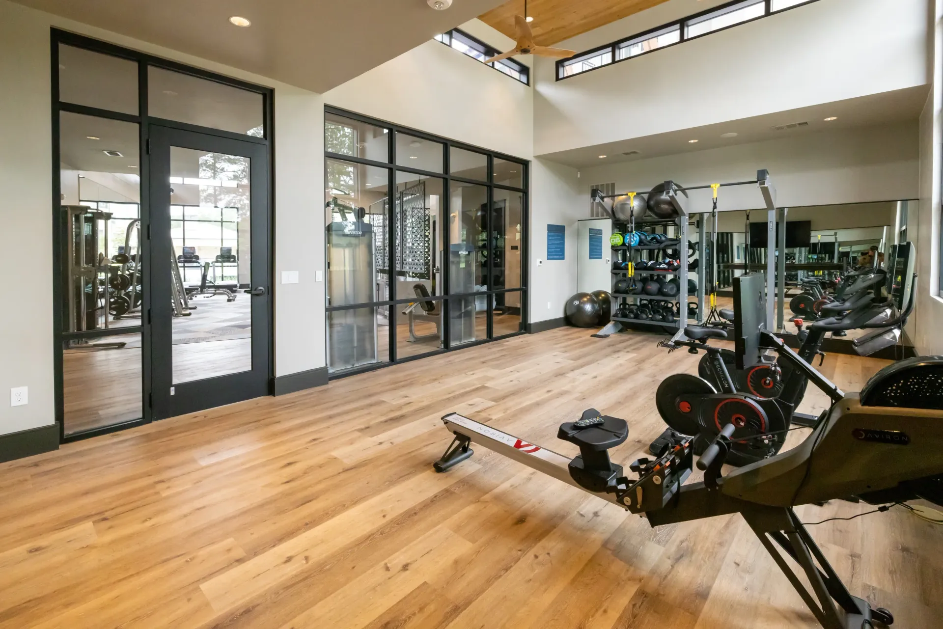 Modern apartment gym with rowing machines, free weights, and cardio equipment.