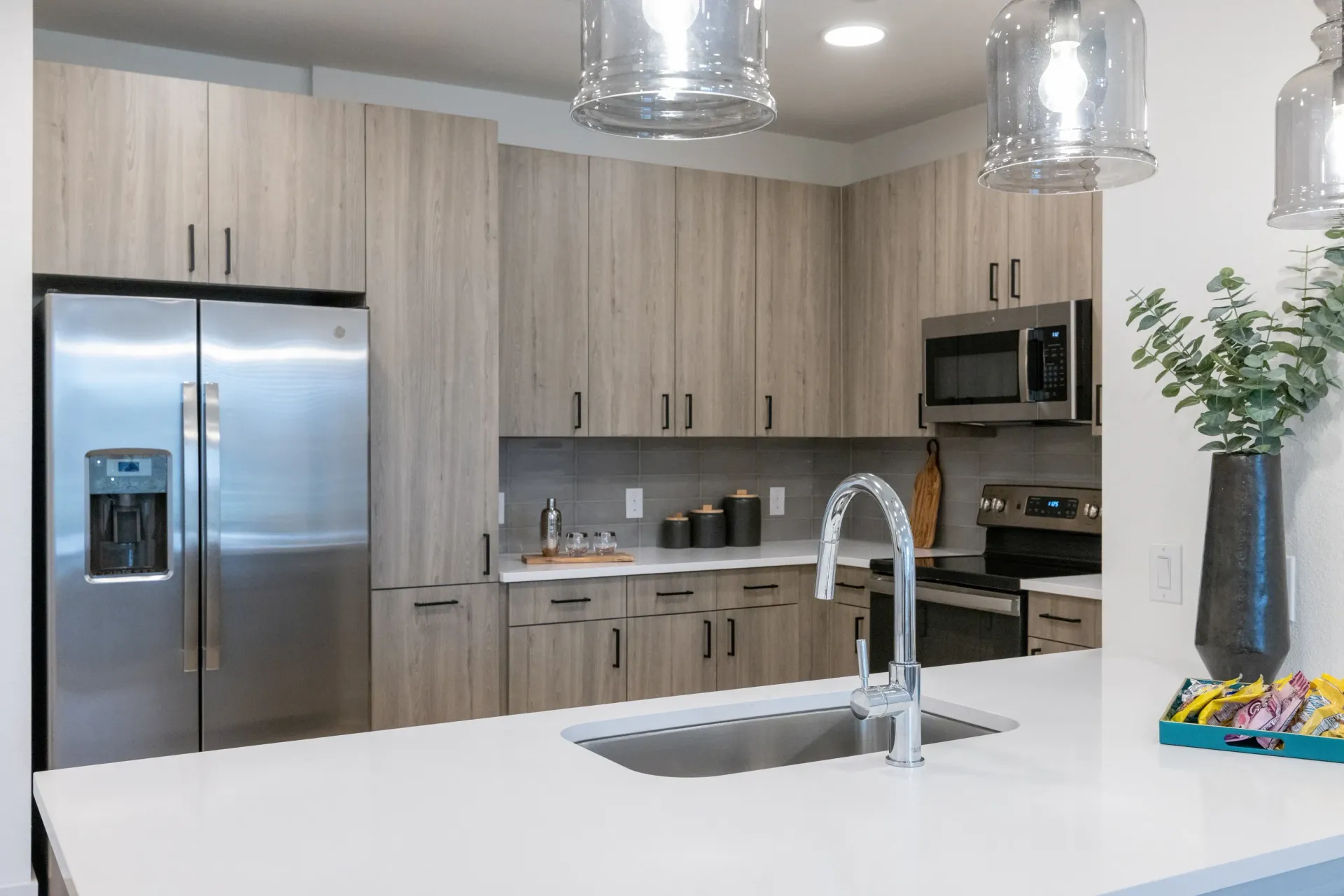 Modern kitchen with stainless steel appliances, light wood cabinets, and a large sink.