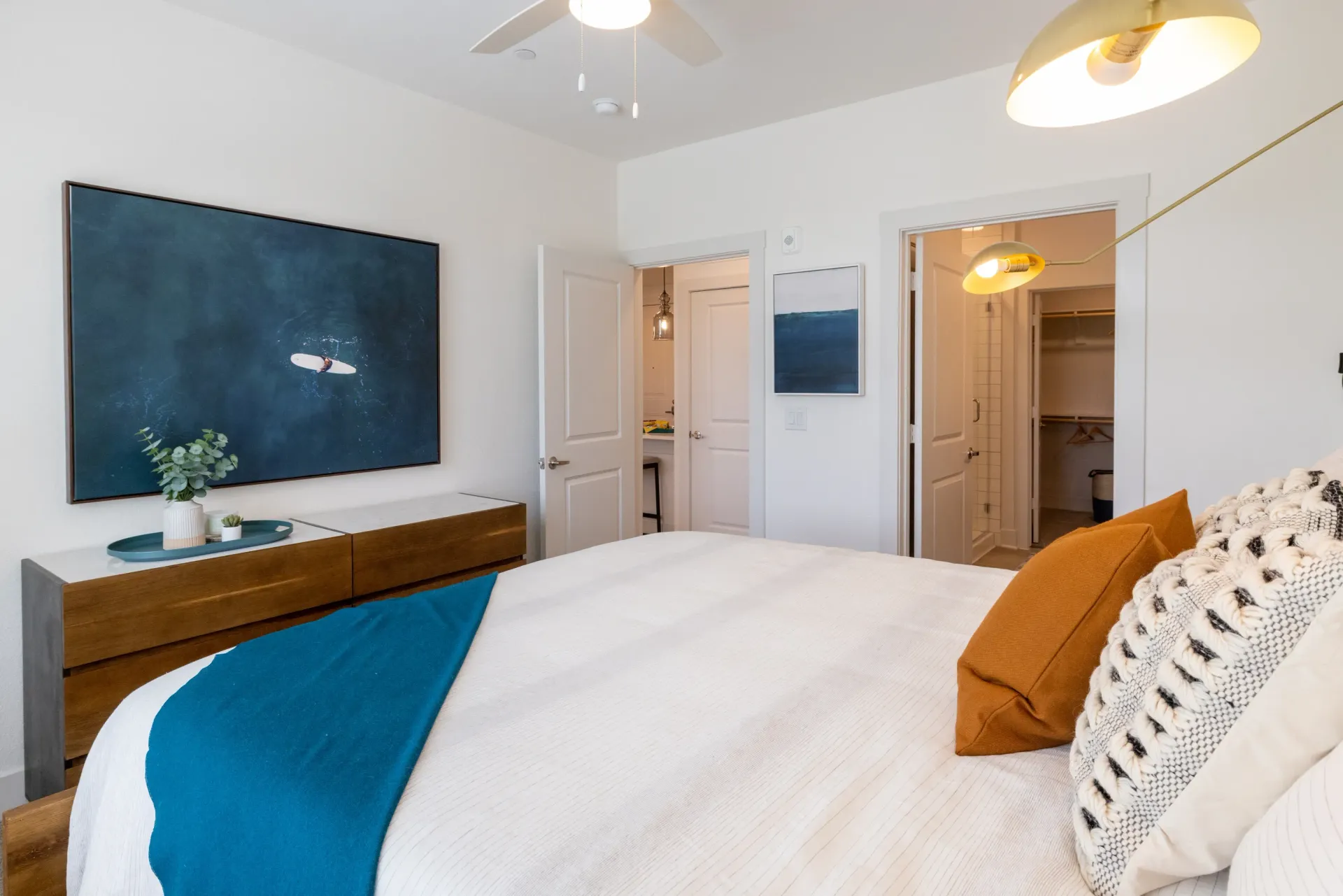 Modern bedroom with large wall art, a dresser, and a walk-in closet.