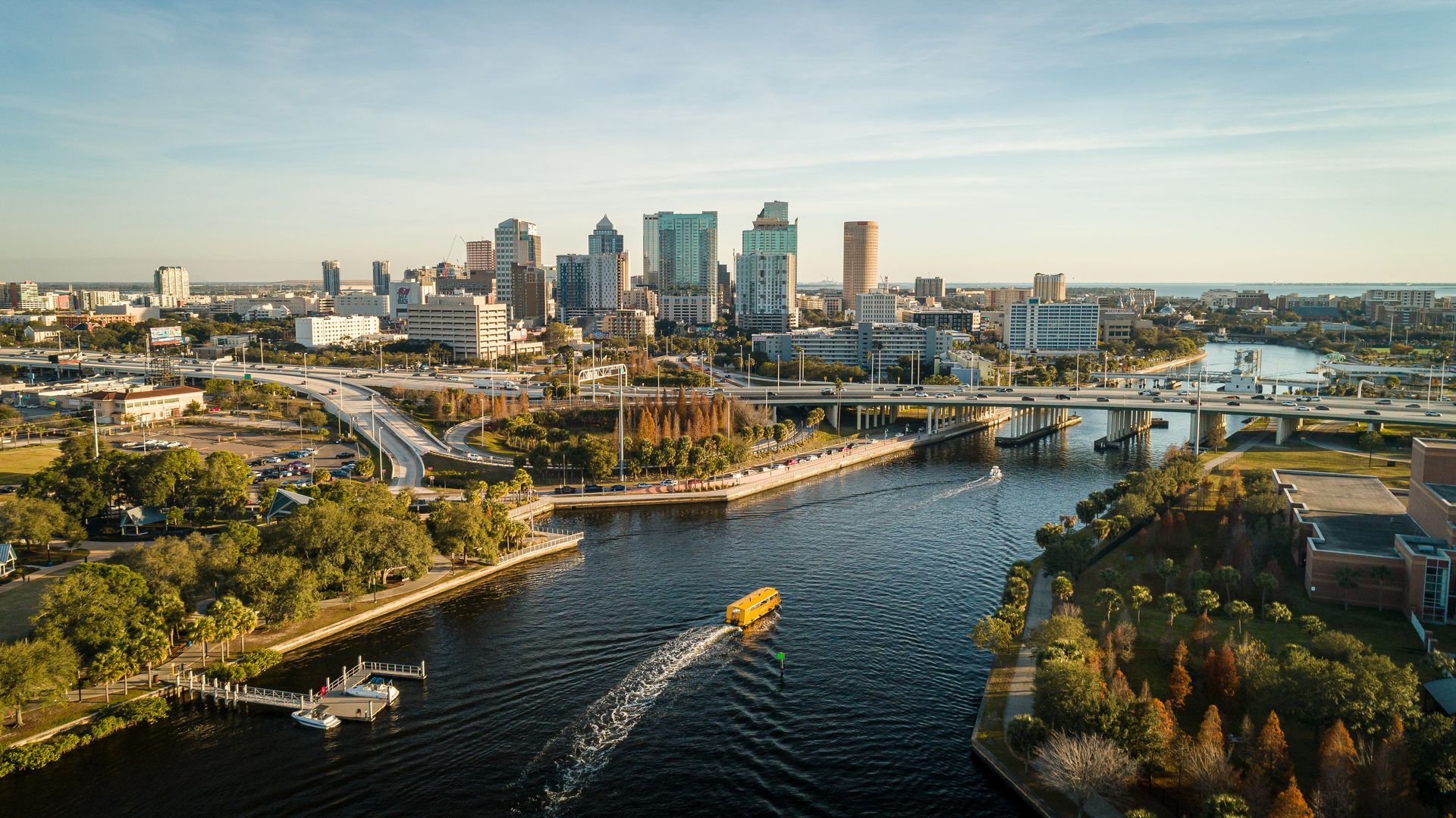 Aerial view of Tampa, Florida skyline, with a boat on Hillsborough River. Blue water, city buildings.