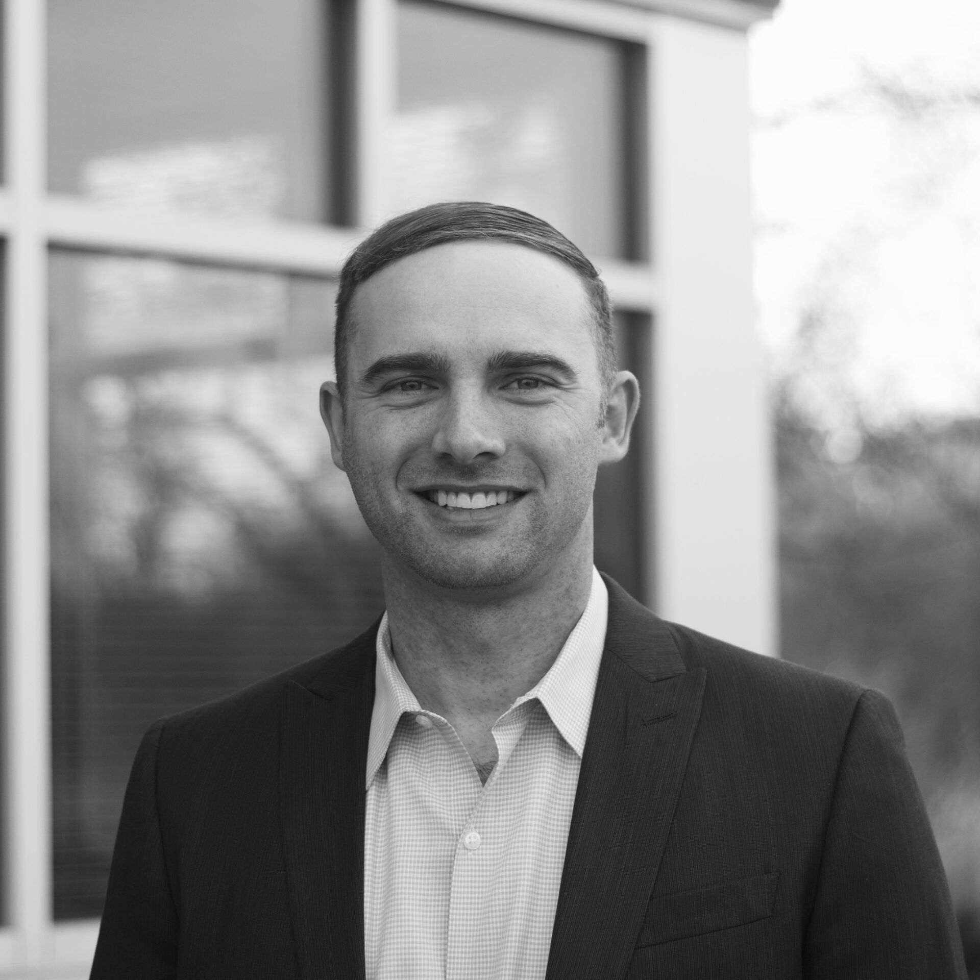 Man in suit smiles in front of a window, wearing a kippah.
