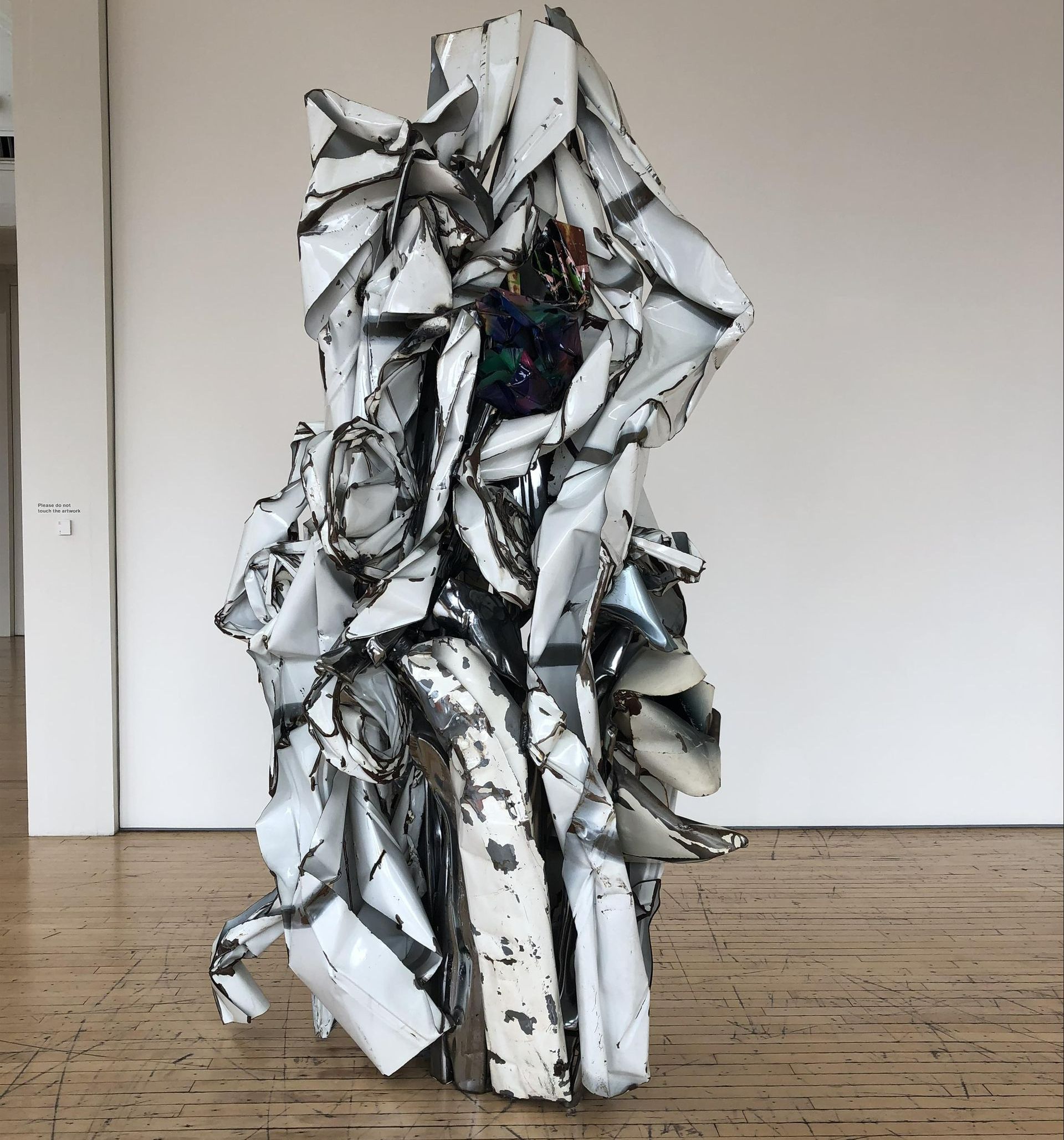 A large white sculpture is sitting on a wooden floor in a room.