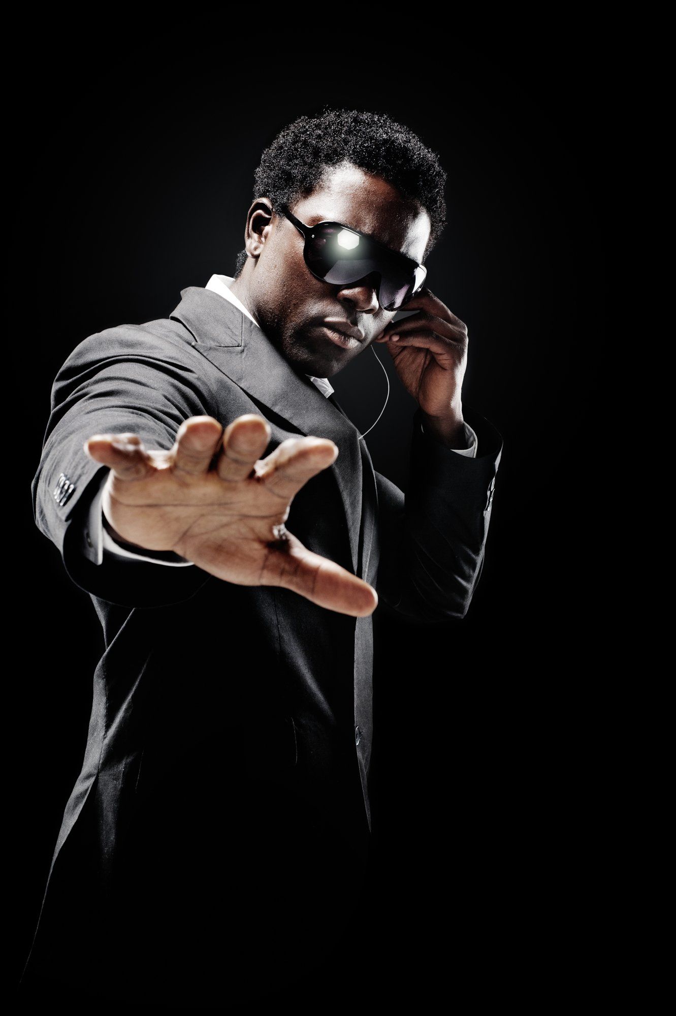 A man in a suit and sunglasses is talking on a cell phone