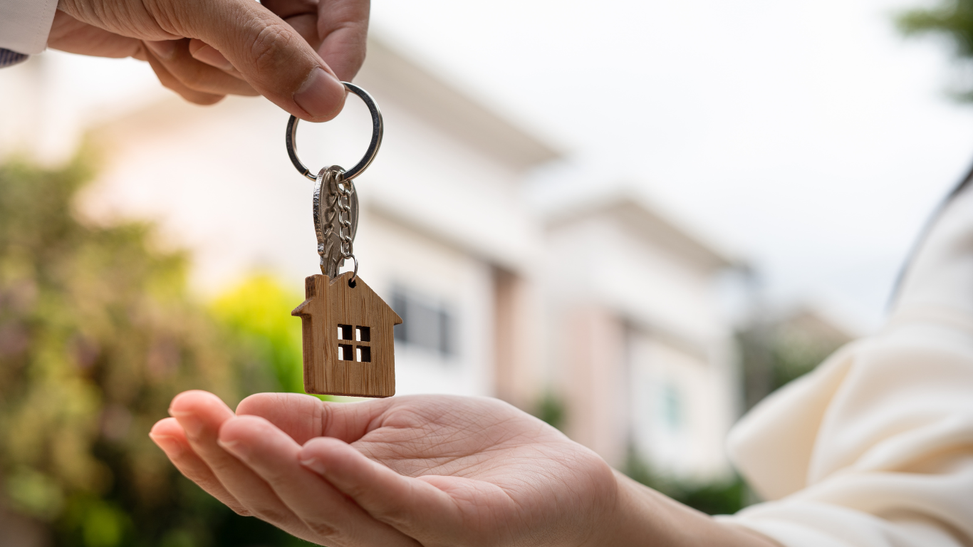 A person is handing a house key to another person.