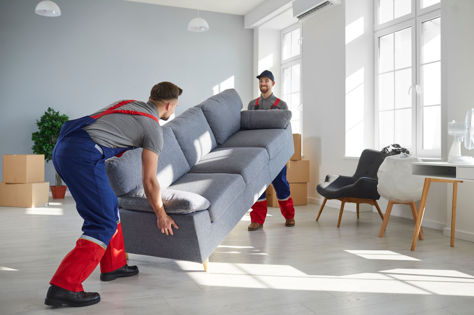 Two men moving a couch in a living room, representing reliable moving companies.
