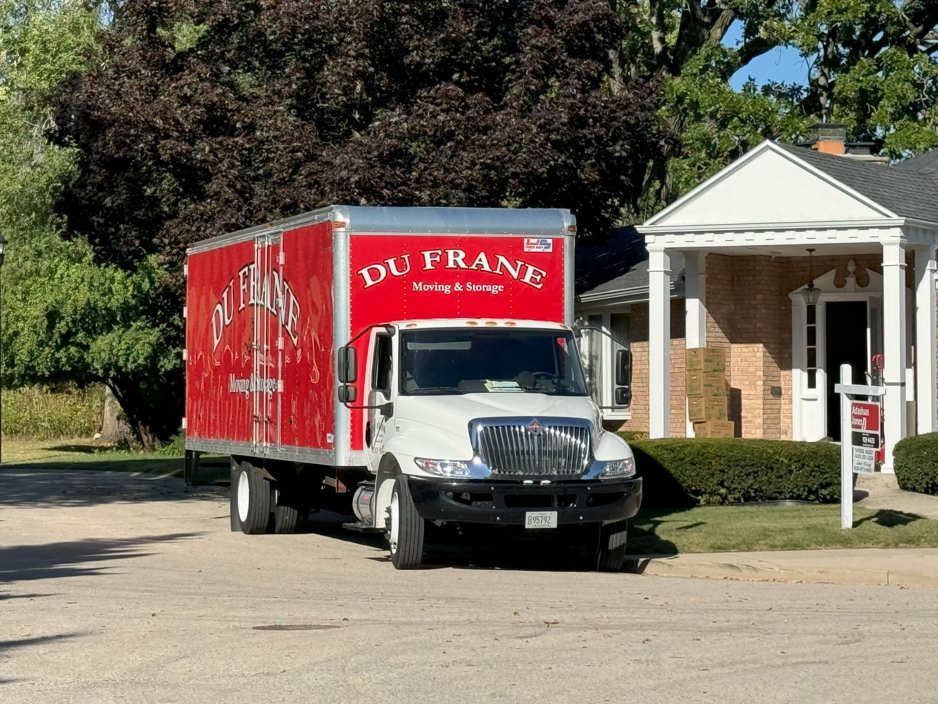 Red DuFrane delivery truck parked in front of a brick building with white columns.