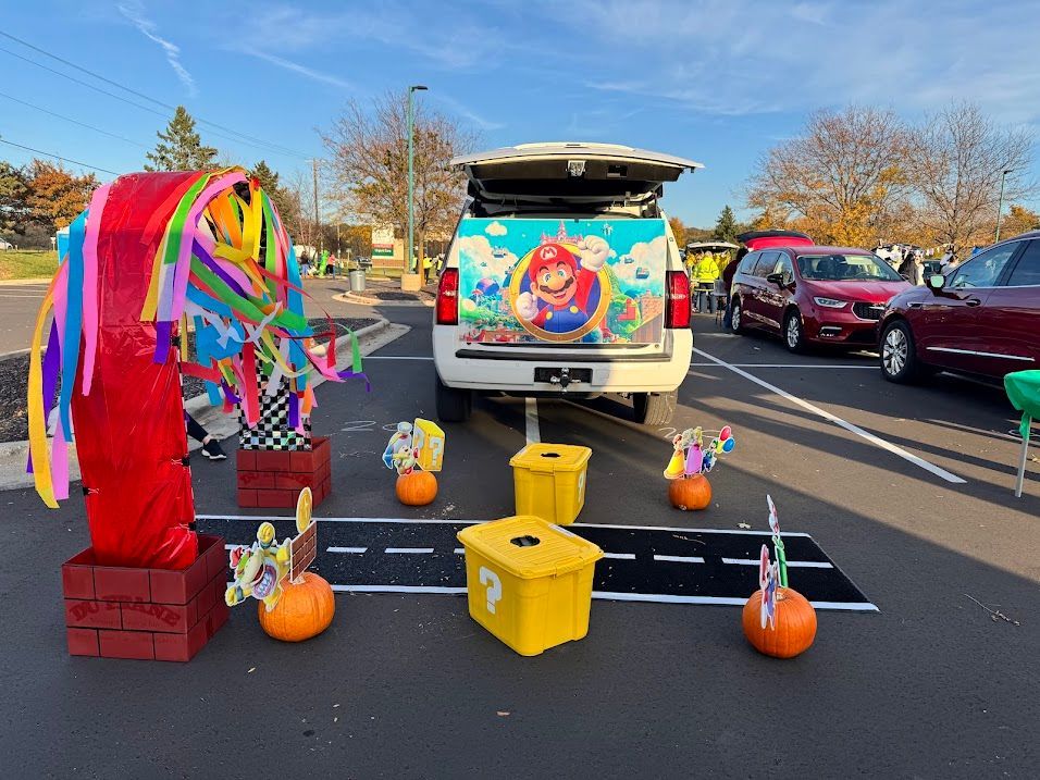 Colorful decorated van with ribbons and pumpkins in a parking lot, likely a festive trunk-or-treat display