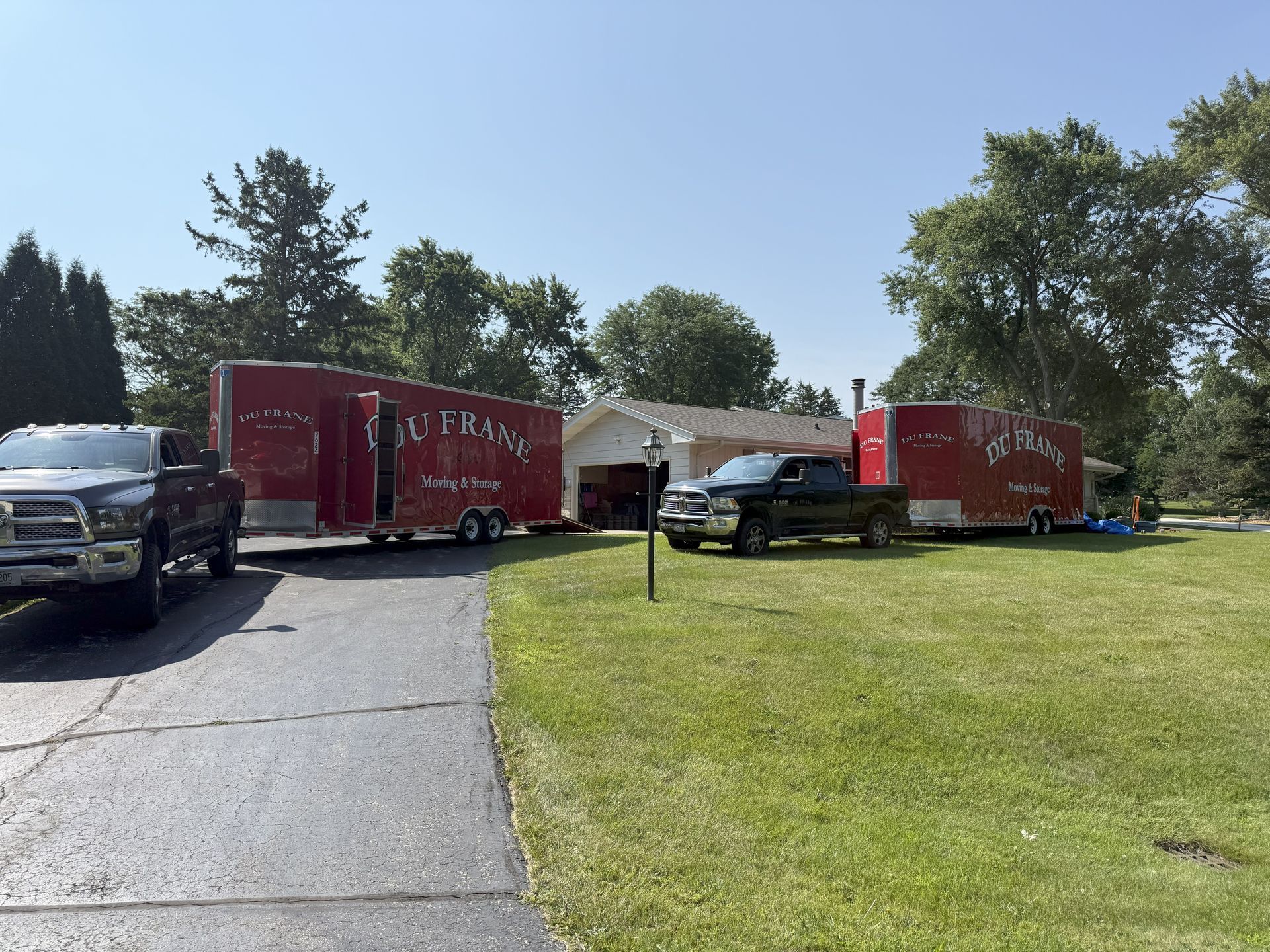 Moving trucks and SUVs parked outside a house on a sunny day
