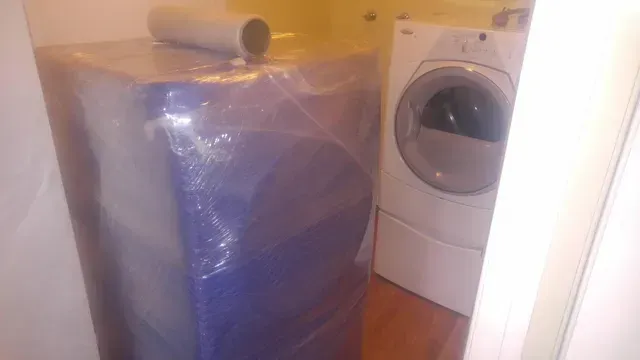 A large, blue-wrapped item and a white washing machine are in a room.