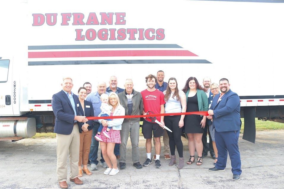 People posing at a ribbon-cutting ceremony in front of a Dufrane Logistics truck