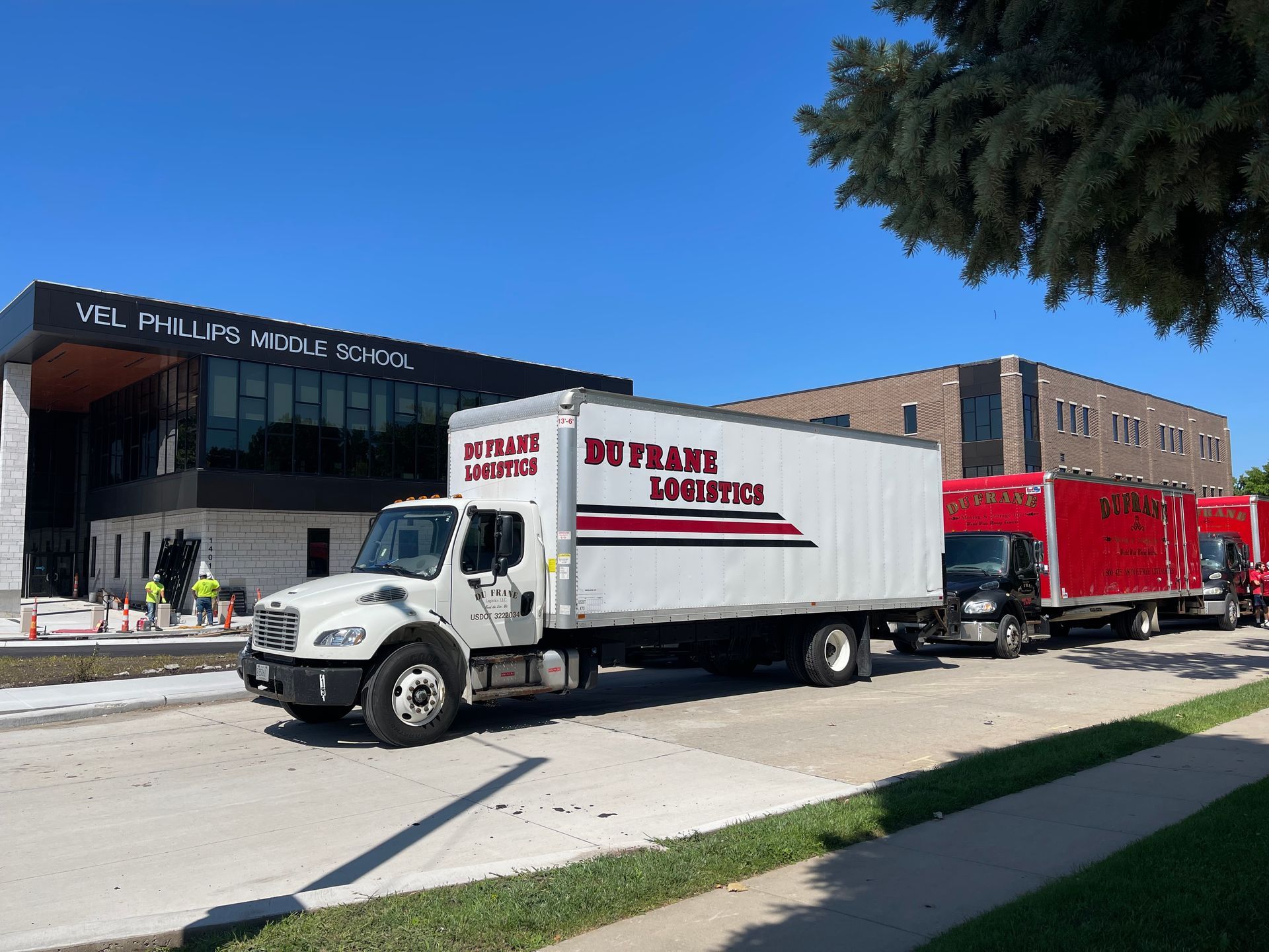 Trucks parked in front of a school, one labeled 