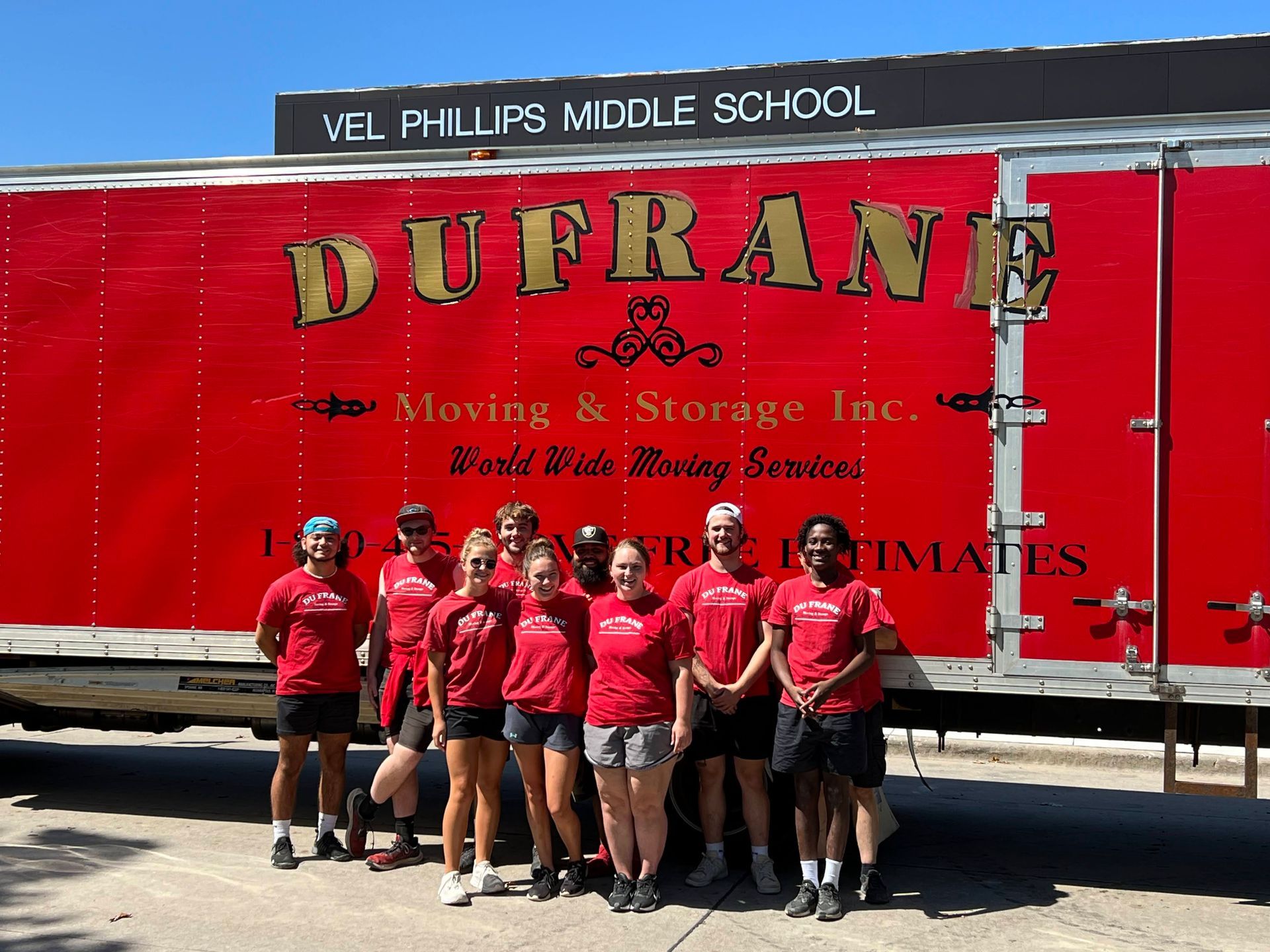 Group of people in red shirts stand in front of a red 