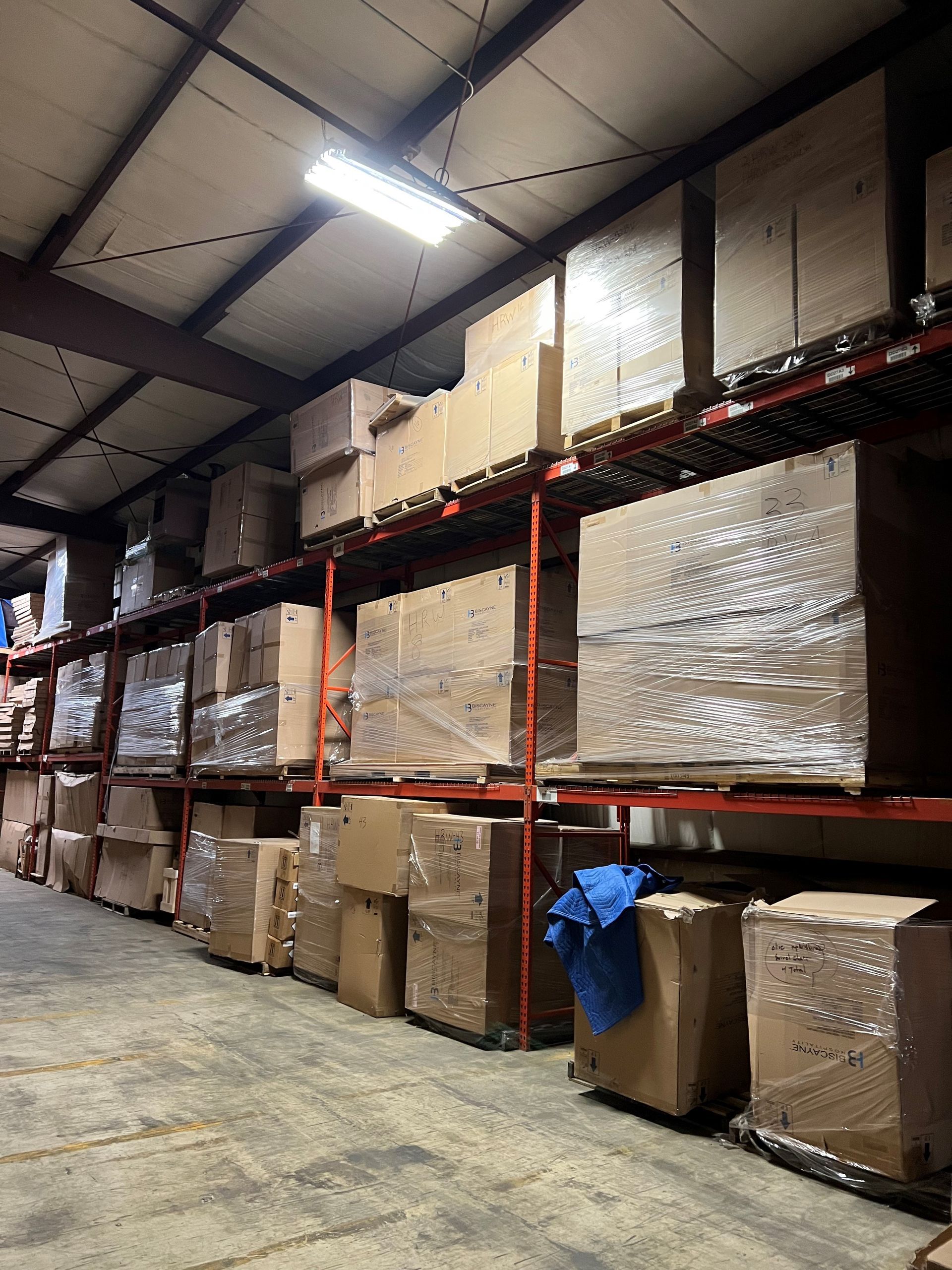 Warehouse interior with boxes stored on tall metal shelves.